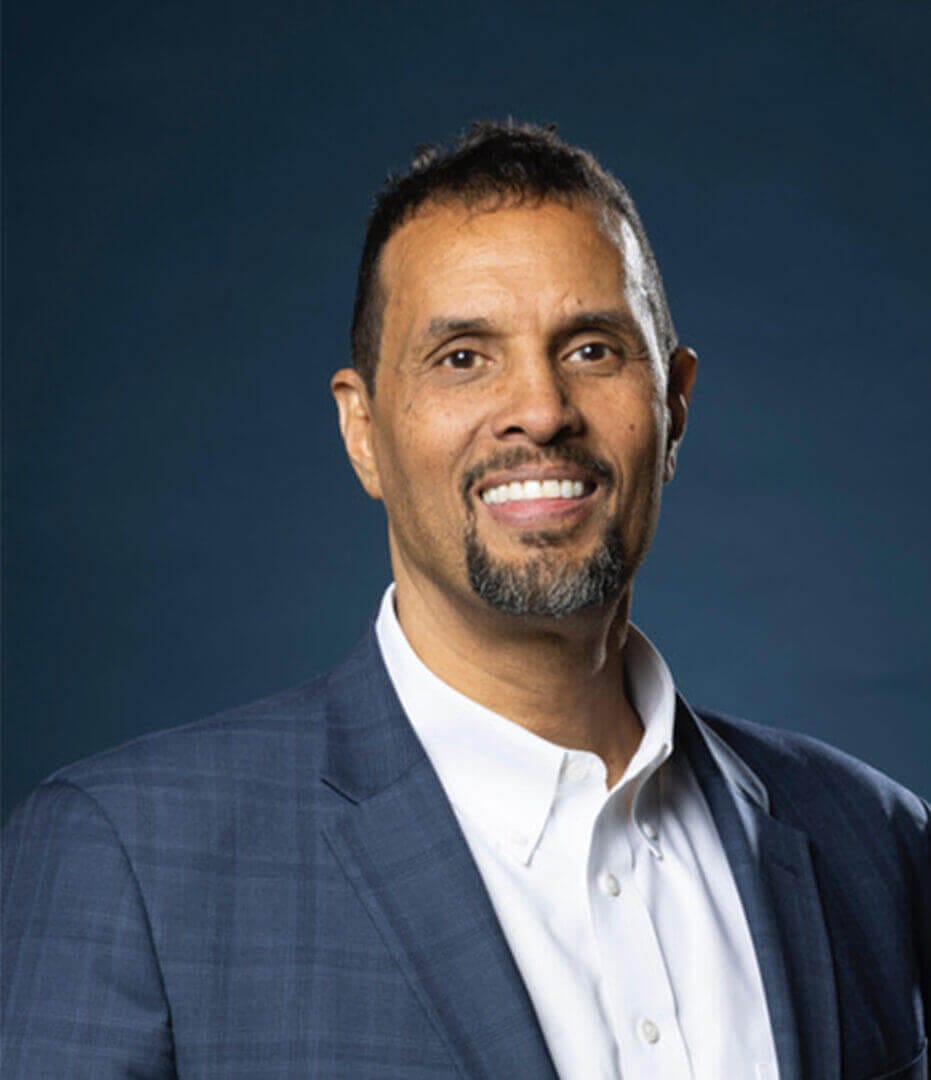 Smiling professional in a blue suit, representing Ceek Next Innovations' leadership, only available at Ceek Next Innovations.